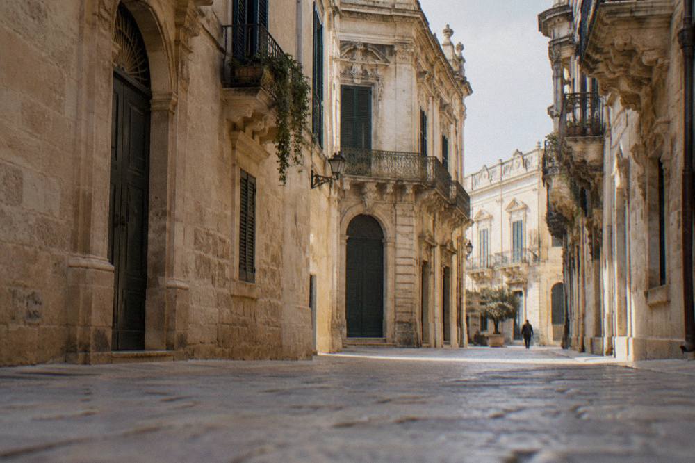 A shaded stone street in Lecce with sunlight on pale walls at midday
