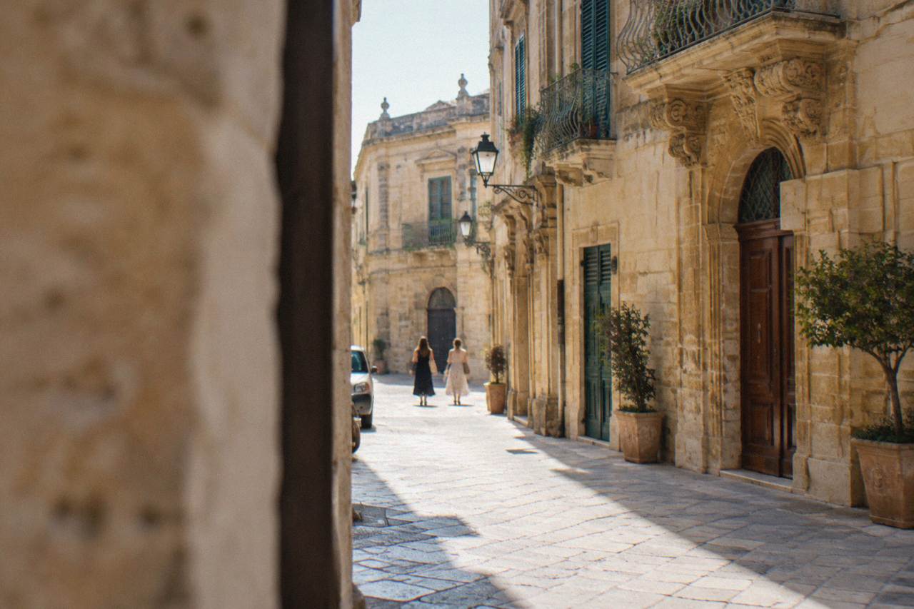 A narrow honey-coloured street in Lecce's old town with a limited traffic zone sign on the wall