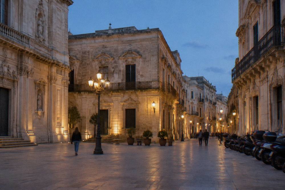 A car-free baroque square in Lecce with parked scooters along one side