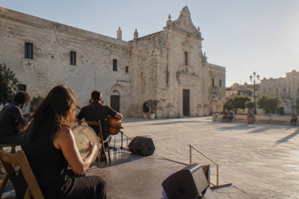Musicians playing tambourines and traditional string instruments on an outdoor stage