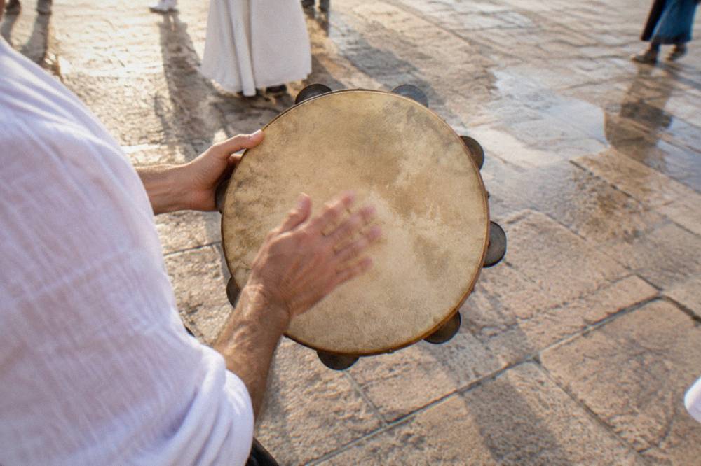 A close view of hands beating a traditional Salento tambourine during a dance