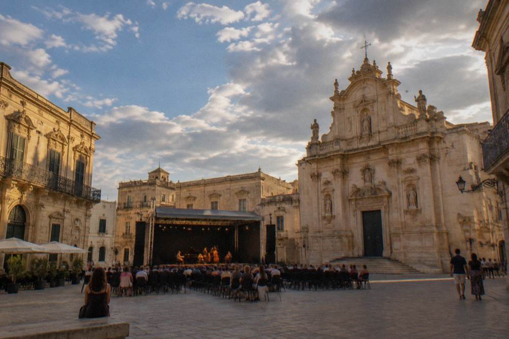A small Salento town square with baroque facades lit for an evening concert