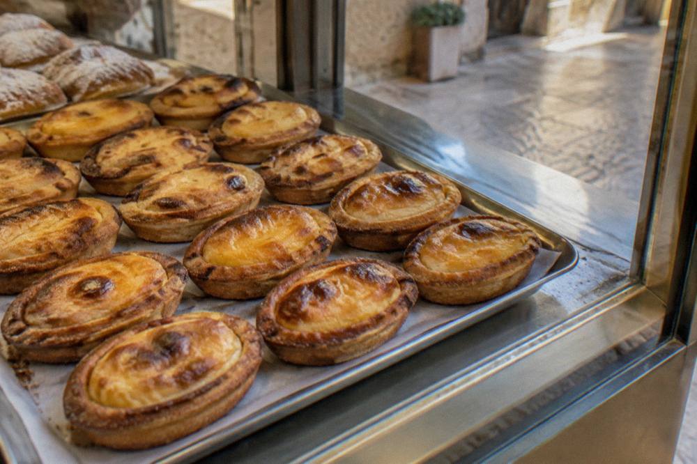 A tray of oval pasticciotti pastries arranged in a bakery display case