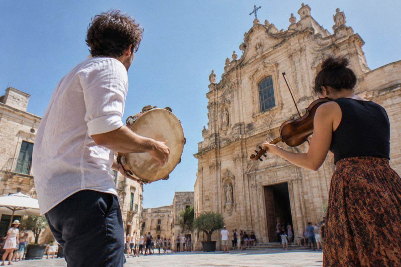 Musicians playing tamburello and violin at an outdoor summer festival in a southern Italian square