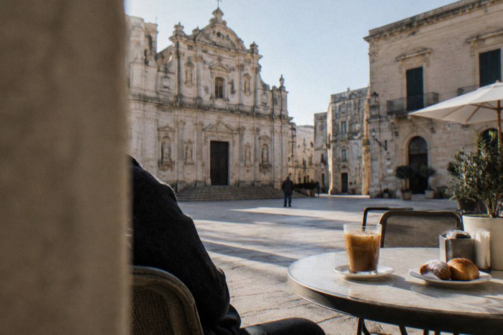 A table with iced coffee in a glass and small pastries on a sunny café terrace in southern Italy