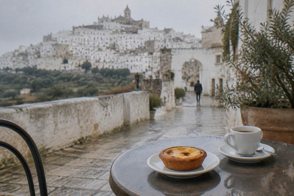 A pasticciotto custard tart on a small plate beside an espresso cup