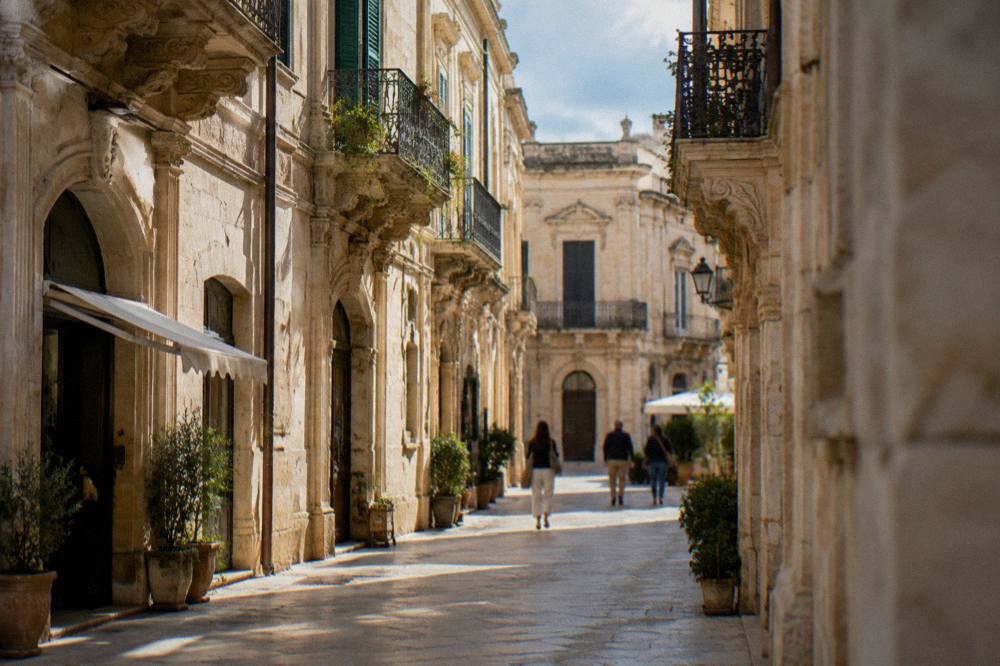 A narrow stone street in Lecce's old town lined with warm limestone buildings and small shops
