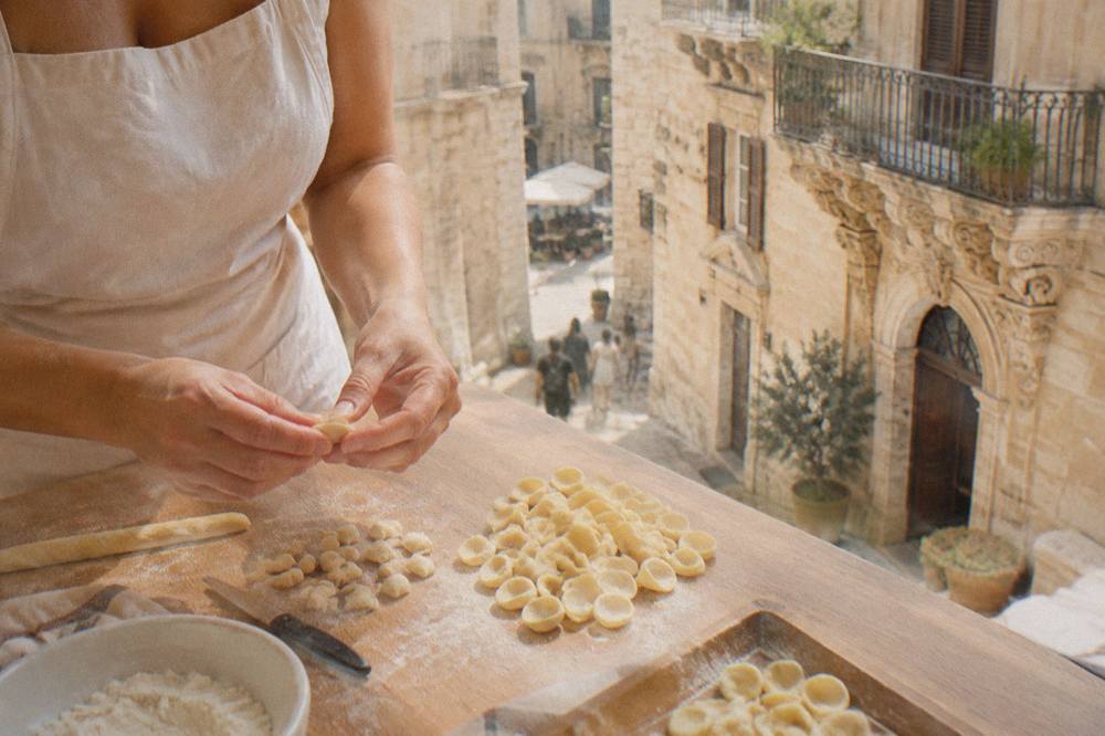 Hands shaping fresh pasta dough on a wooden table in a Lecce cooking class