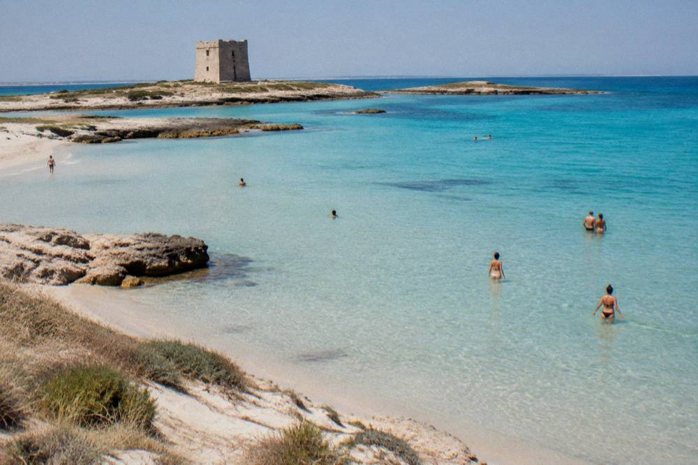 Wide shallow sandy beach with dunes and clear turquoise water on the Ionian coast
