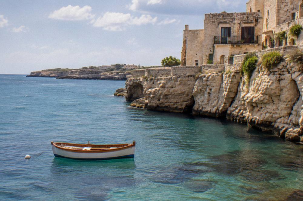 A wooden boat anchored near limestone cliffs on the Adriatic coast