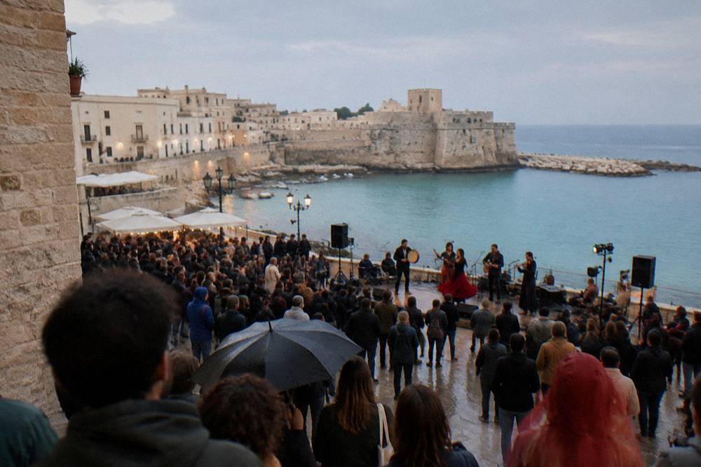 Crowds at an outdoor pizzica music concert in a southern Italian town square
