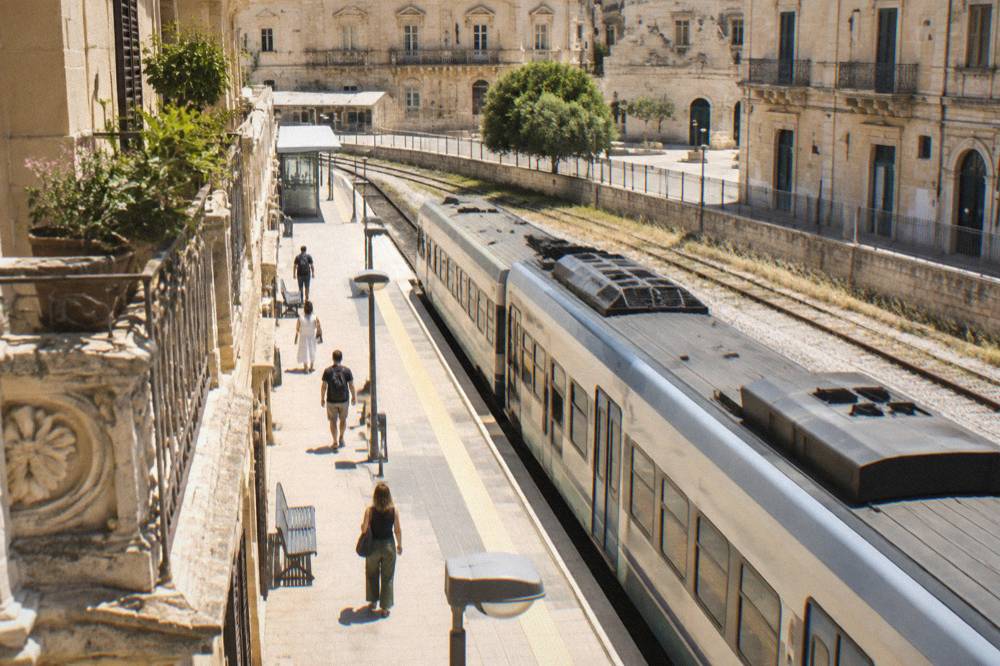 A regional train waiting at a sunny platform in a southern Italian rail station