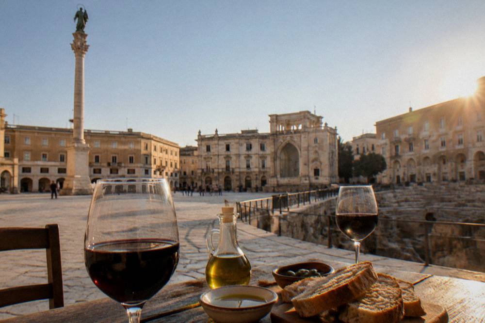 Glasses of dark Negroamaro wine on a rustic table with olive oil and bread in Salento