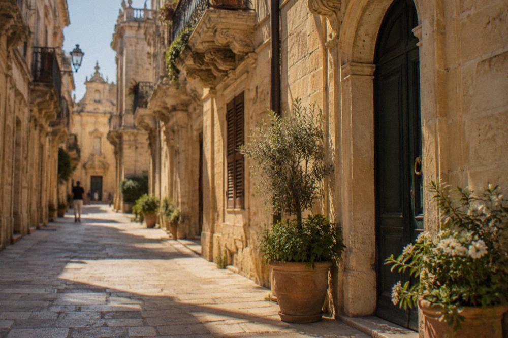A quiet old town street in Lecce with limestone facades and potted plants by a doorway