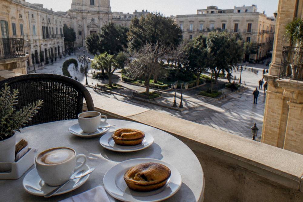 A hotel breakfast table set with coffee and pasticciotto pastries on a terrace