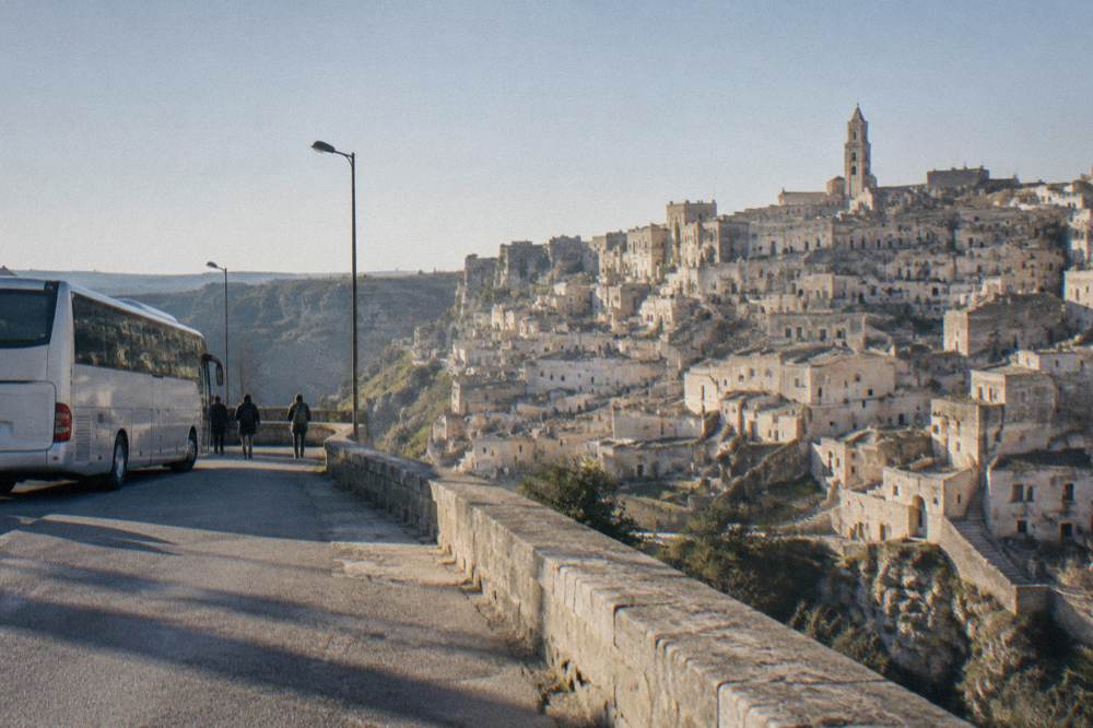 A long-distance bus parked at a southern Italian roadside station in morning light