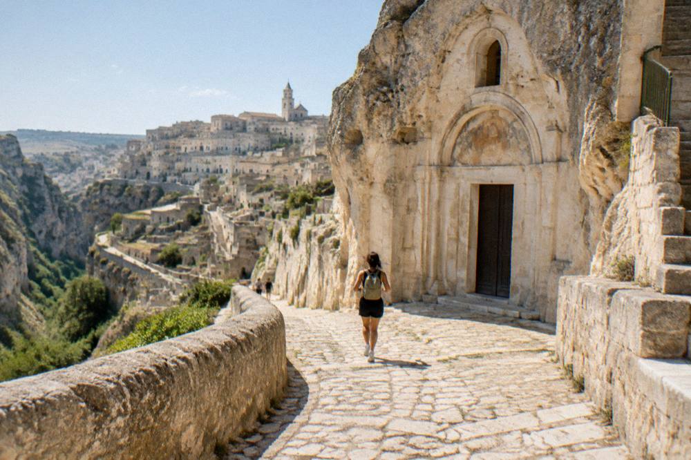 Cave church facade cut into pale rock above a stone street in Matera