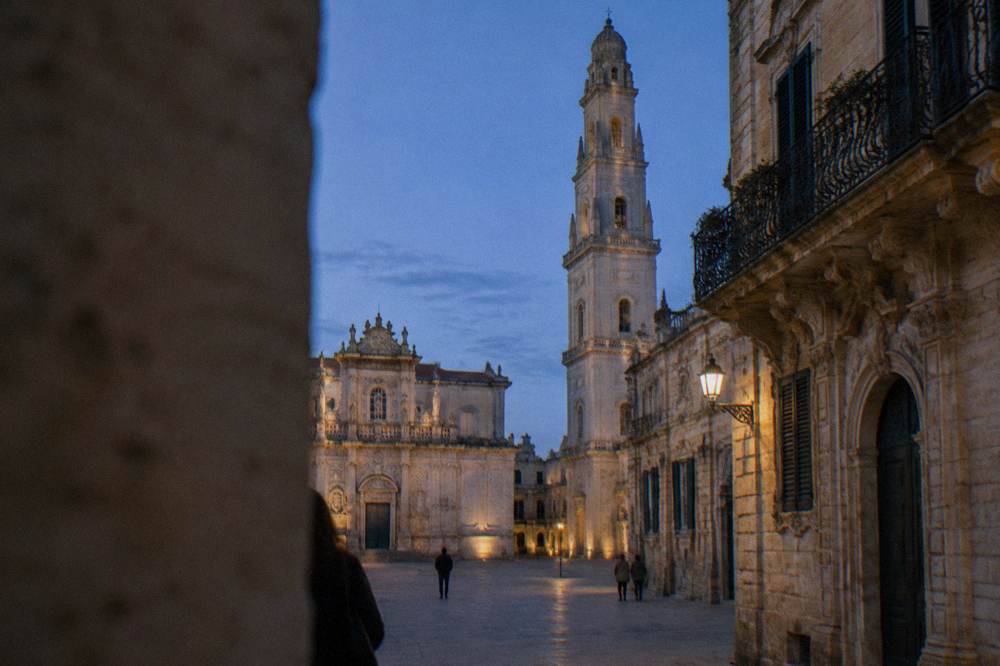 The tall baroque bell tower and cathedral facade enclosing a quiet Lecce piazza