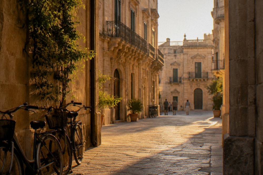 Golden late afternoon light on a limestone street in Lecce with bicycles parked by a wall