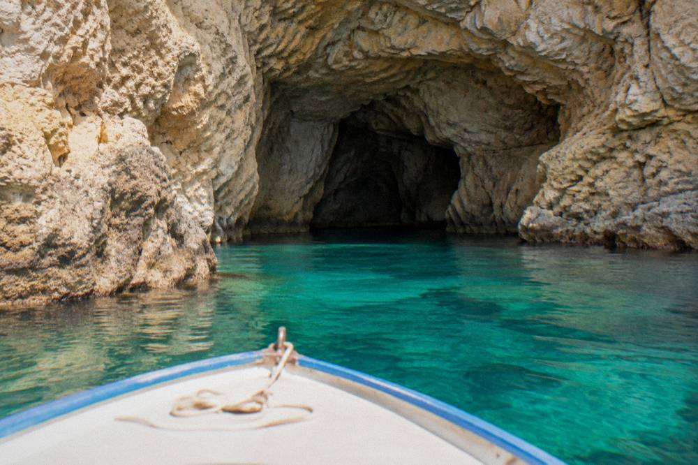 A small boat entering a sea cave along a rocky coastline