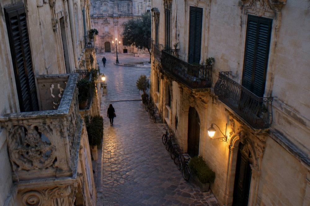 A narrow stone street in Lecce lined with baroque buildings and parked bicycles