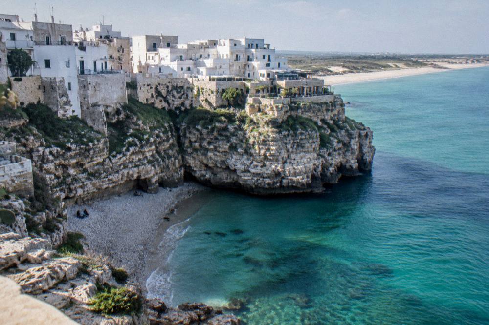 A sandy Ionian beach with shallow turquoise water and dunes behind it