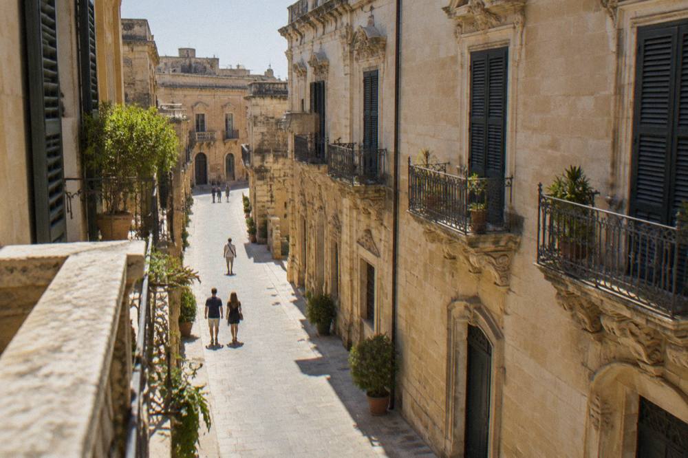 A narrow stone street in Lecce's old town with warm limestone walls and balconies