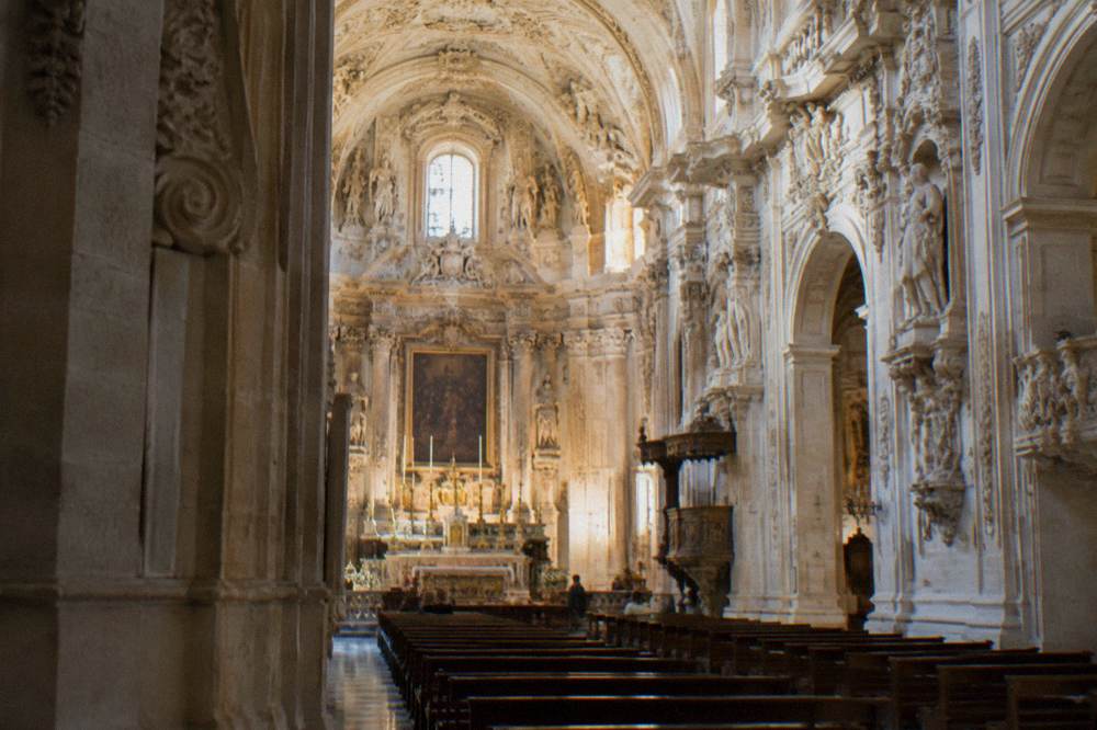 The ornate interior of a baroque church in Lecce with a carved stone ceiling