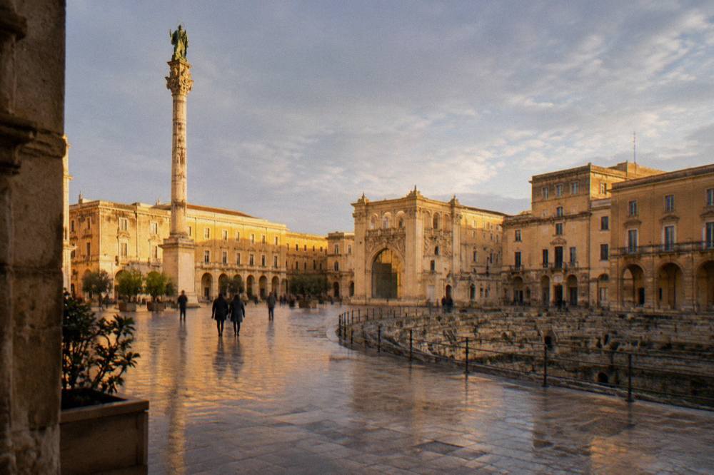 Lecce's limestone buildings glowing in low golden evening light in a piazza